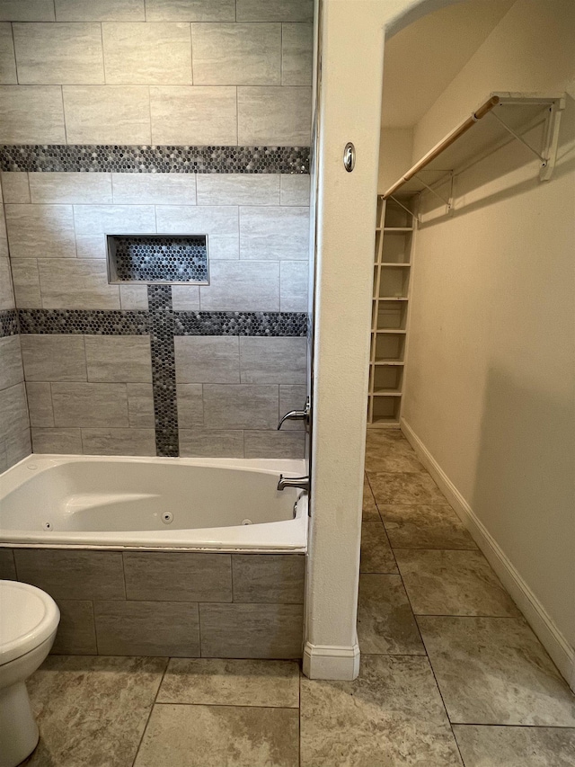 bathroom featuring tiled shower / bath combo, tile patterned flooring, and toilet