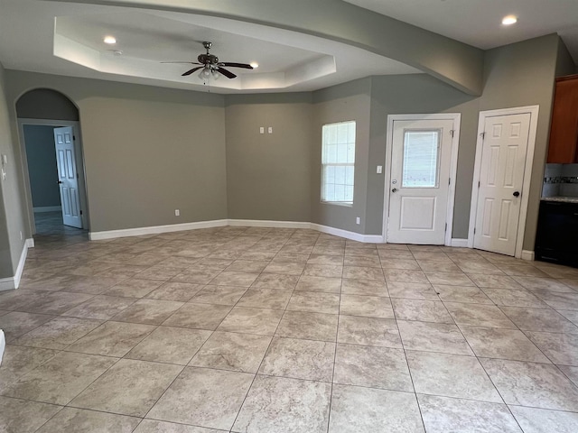 interior space with ceiling fan, light tile patterned floors, and a tray ceiling