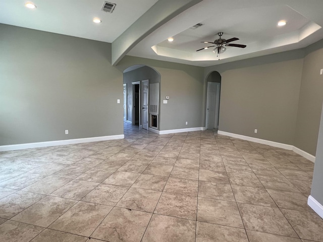 tiled spare room with ceiling fan and a tray ceiling