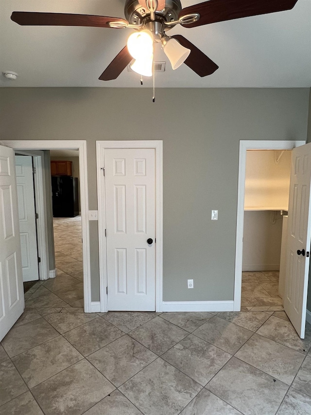 unfurnished bedroom with black refrigerator and ceiling fan