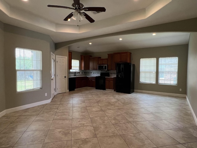 kitchen with light tile patterned floors, sink, a tray ceiling, ceiling fan, and black appliances