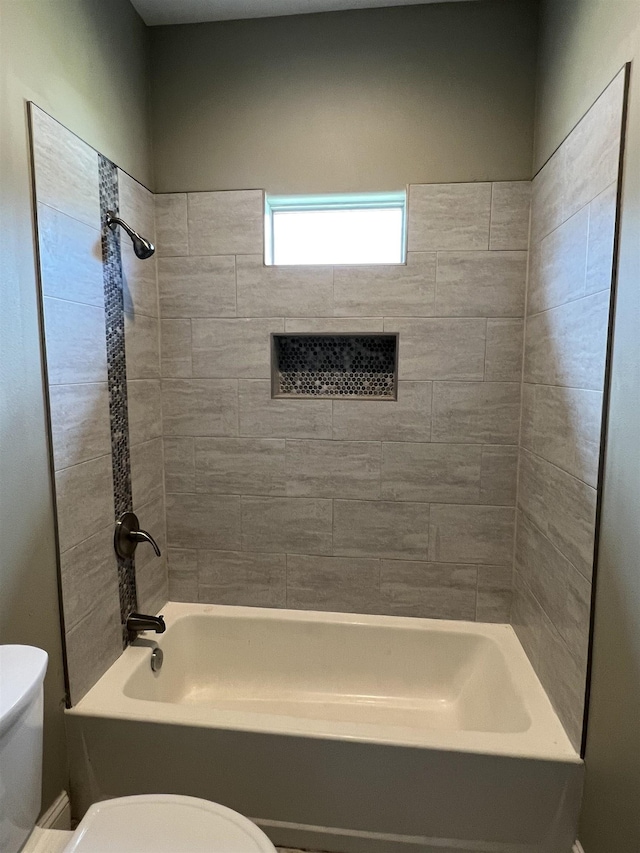 bathroom with toilet and tiled shower / bath combo