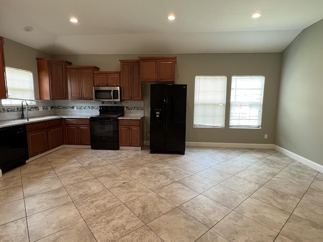 kitchen with tasteful backsplash, black appliances, lofted ceiling, light tile patterned flooring, and sink