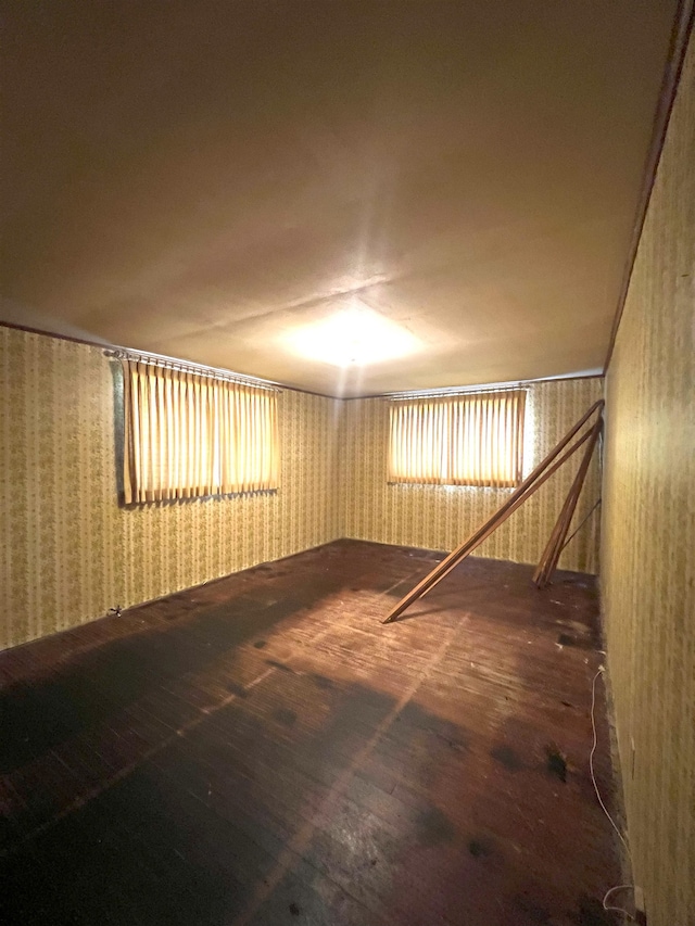 empty room with wood-type flooring and wallpapered walls