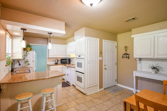 740 Randolph Cir, Beaumont, TX 77706 - kitchen with a sink, white appliances, a peninsula, tasteful backsplash, and light tile patterned flooring