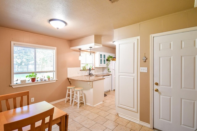 740 Randolph Cir, Beaumont, TX 77706 - kitchen with a peninsula, a sink, a kitchen breakfast bar, white appliances, and white cabinetry