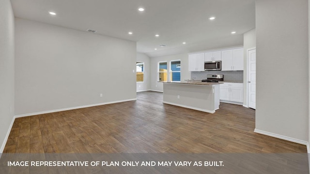 kitchen with tasteful backsplash, stainless steel appliances, dark wood-type flooring, a center island with sink, and white cabinetry