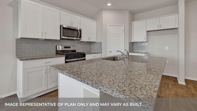 kitchen featuring white cabinets, sink, light stone countertops, an island with sink, and appliances with stainless steel finishes