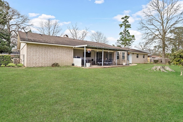 rear view of property with brick siding, fence, a patio, and a yard