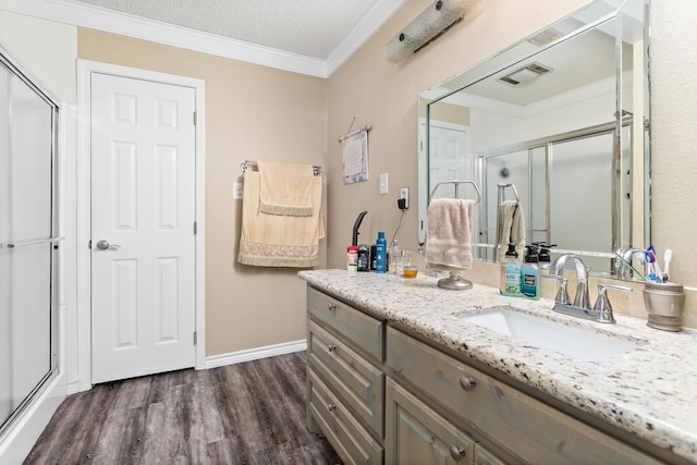 full bath with wood finished floors, vanity, visible vents, a shower stall, and crown molding