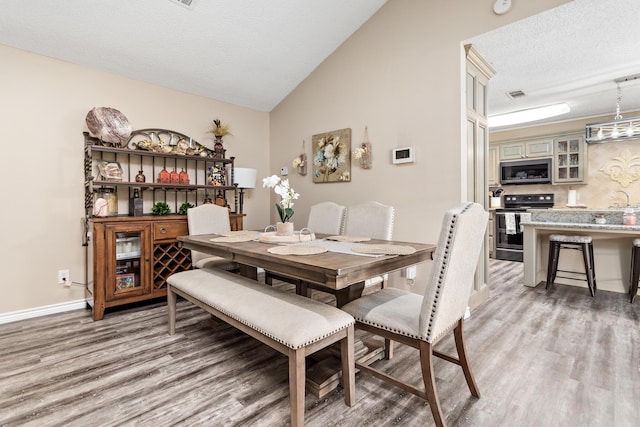 dining area with lofted ceiling, visible vents, a textured ceiling, and light wood finished floors