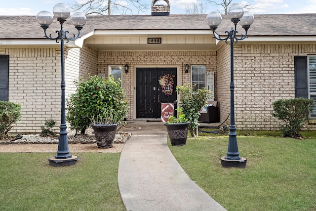 property entrance featuring a yard, brick siding, and a chimney