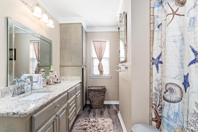 full bath featuring a shower with shower curtain, wood finished floors, vanity, baseboards, and crown molding