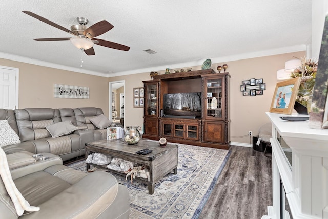 living area featuring dark wood-type flooring, visible vents, ornamental molding, and a textured ceiling