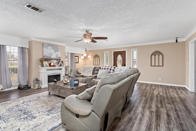 living room featuring dark wood-type flooring, a high end fireplace, visible vents, baseboards, and ornamental molding