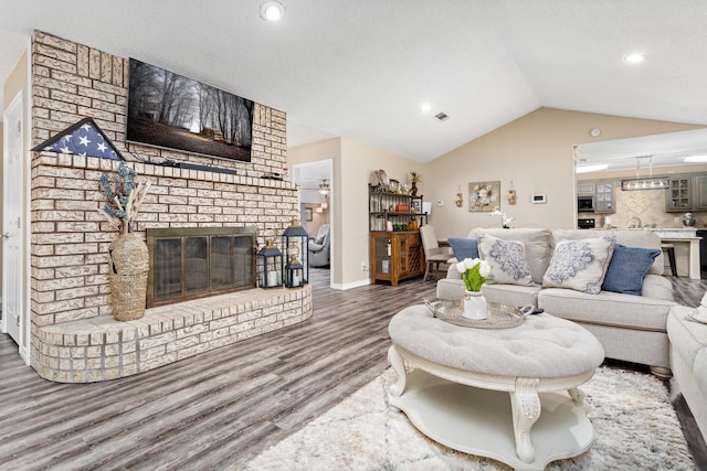 living area with baseboards, visible vents, lofted ceiling, wood finished floors, and a fireplace