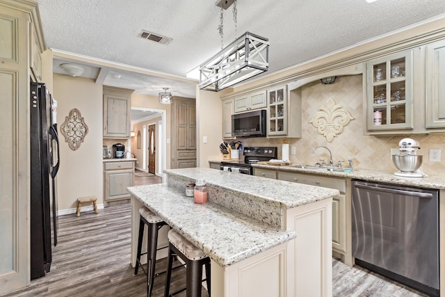 kitchen with visible vents, appliances with stainless steel finishes, a center island, light wood-style floors, and a sink