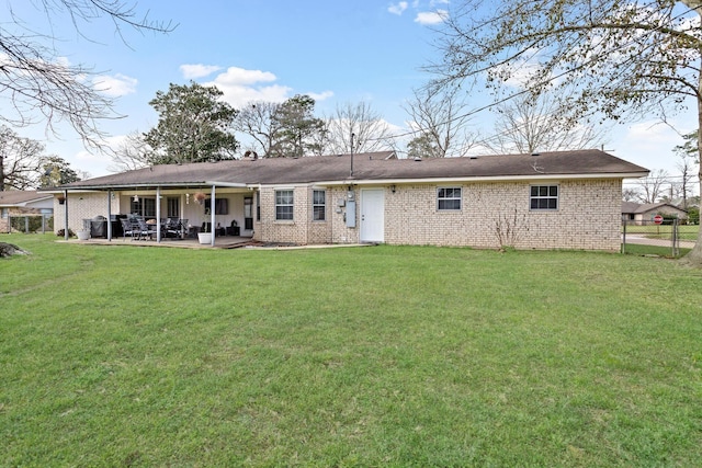 back of house featuring brick siding, fence, a patio, and a yard