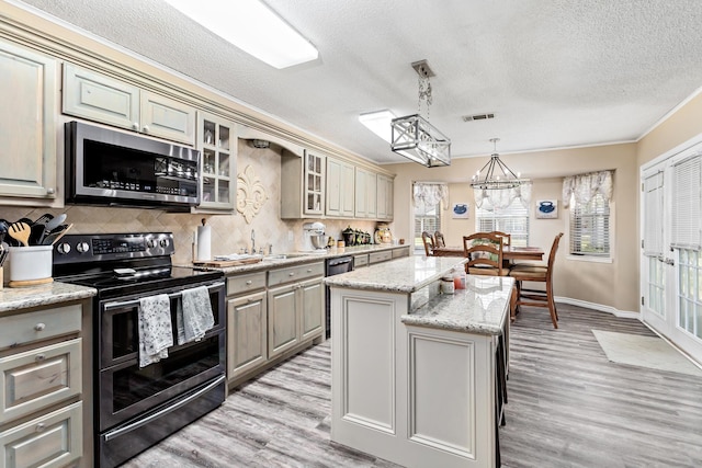 kitchen featuring stainless steel appliances, backsplash, glass insert cabinets, light wood-style floors, and a kitchen island