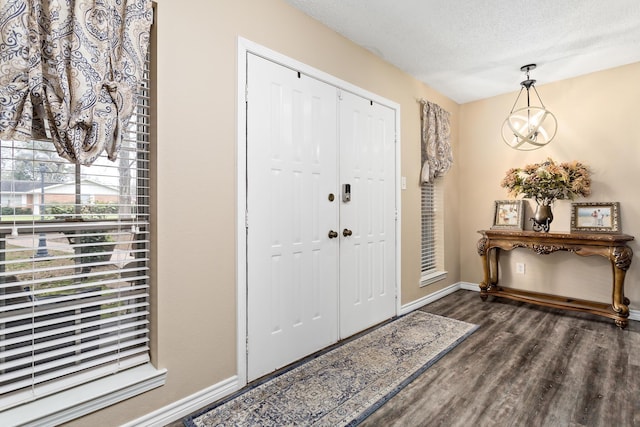 entrance foyer with a notable chandelier, baseboards, dark wood finished floors, and a textured ceiling