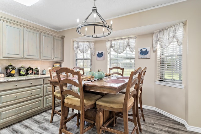 dining space with baseboards, wood finished floors, an inviting chandelier, crown molding, and a textured ceiling