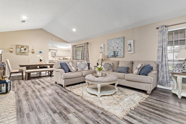 living room featuring lofted ceiling, wood finished floors, and visible vents