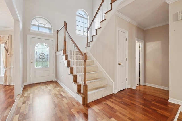 foyer entrance featuring ornamental molding, stairway, baseboards, and wood finished floors