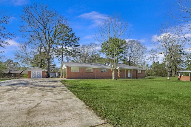 single story home with a storage shed, concrete driveway, a front lawn, and an outbuilding