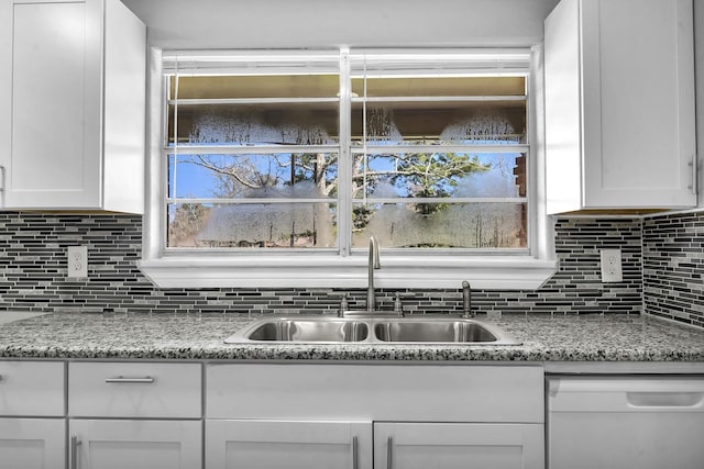 kitchen featuring dishwasher, light stone counters, a sink, and white cabinetry