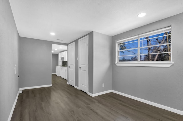 spare room with dark wood-style floors, visible vents, baseboards, and recessed lighting