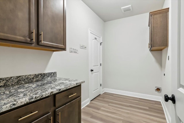 clothes washing area with cabinets and light wood-type flooring