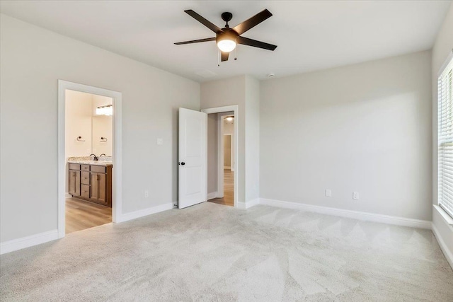 unfurnished bedroom featuring light carpet, ensuite bath, and ceiling fan