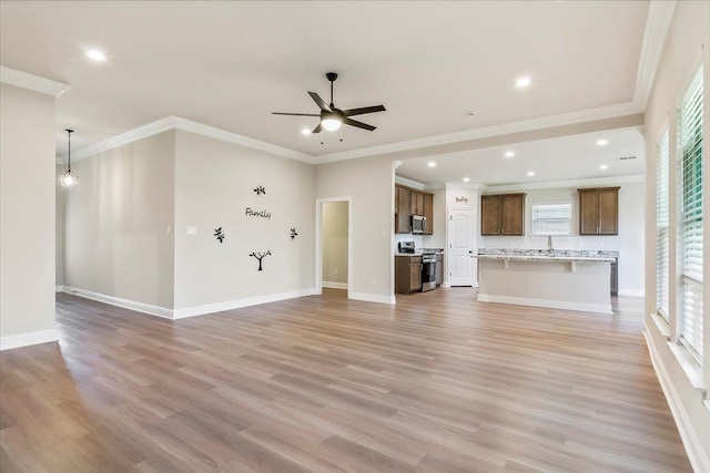 unfurnished living room featuring ceiling fan, sink, light wood-type flooring, and ornamental molding