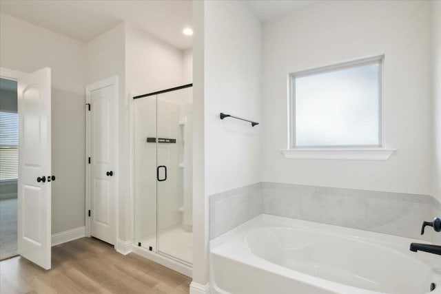 bathroom with shower with separate bathtub and hardwood / wood-style flooring