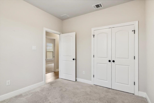 unfurnished bedroom with light colored carpet and a closet