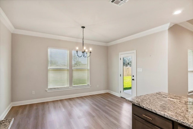 unfurnished dining area featuring a wealth of natural light, crown molding, light hardwood / wood-style floors, and a notable chandelier