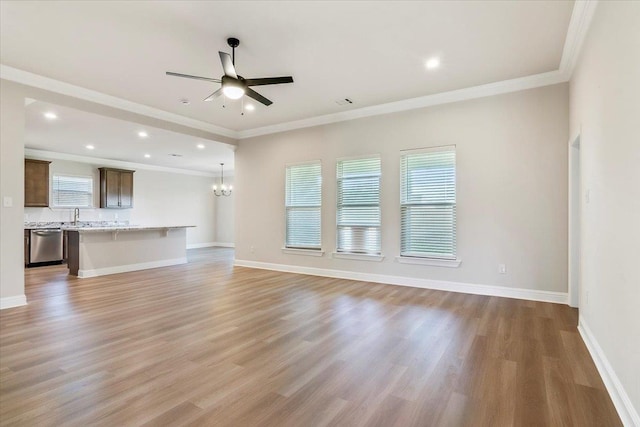 unfurnished living room featuring sink, light hardwood / wood-style flooring, ceiling fan with notable chandelier, and ornamental molding