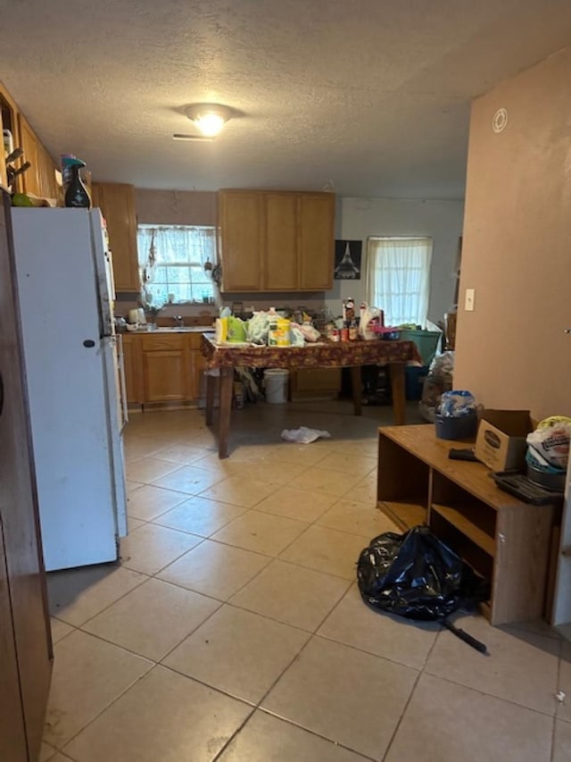 kitchen with light tile patterned flooring, white fridge, and a textured ceiling