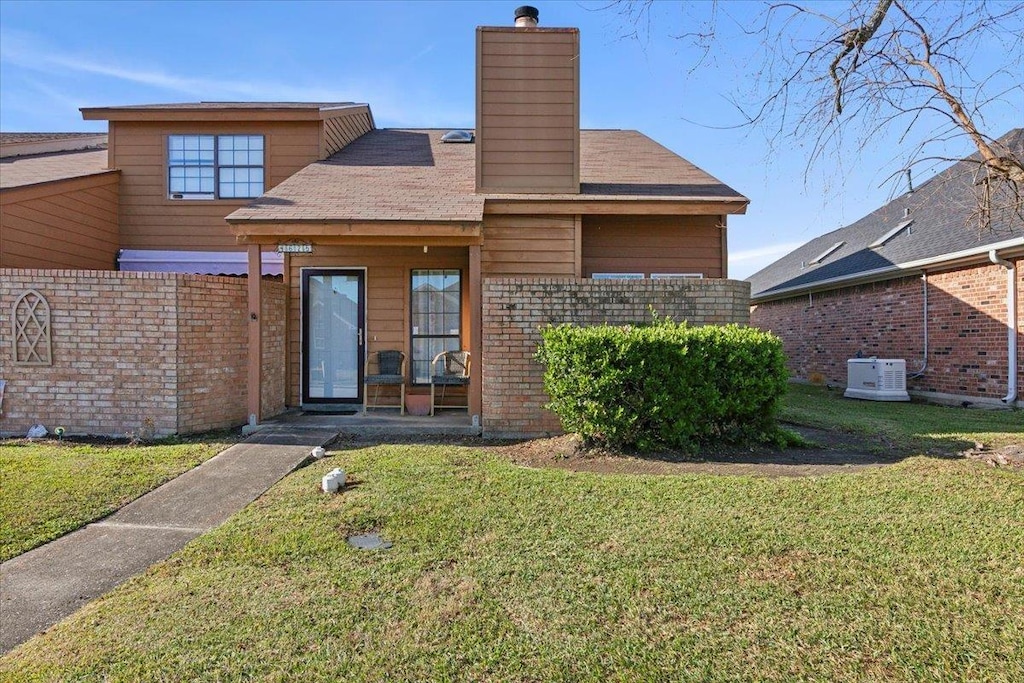 rear view of property with central AC unit and a yard