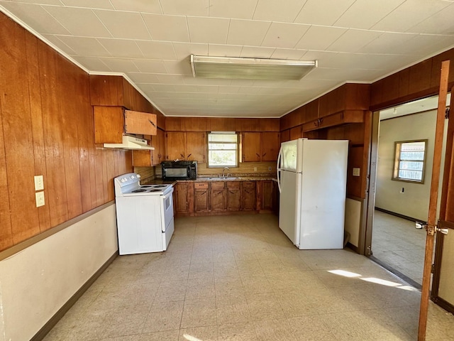 kitchen with crown molding, sink, white appliances, and wooden walls