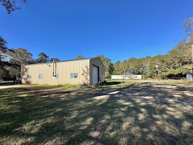 view of side of home featuring a lawn, a garage, and an outdoor structure