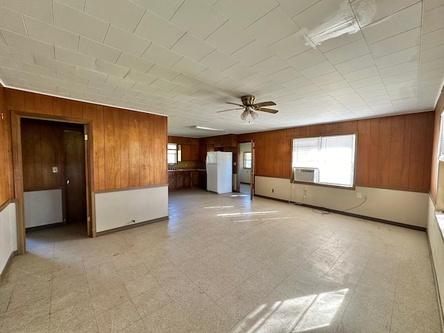 unfurnished living room with ceiling fan, wood walls, and cooling unit