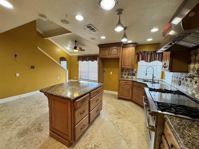 kitchen with ceiling fan, sink, a center island, extractor fan, and ornamental molding