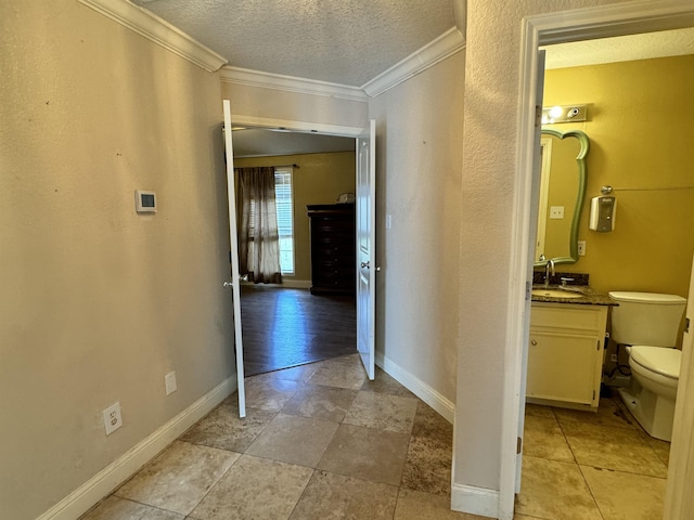 corridor with a textured ceiling, ornamental molding, and sink