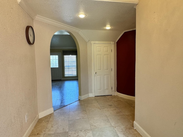 corridor featuring lofted ceiling, a textured ceiling, and ornamental molding