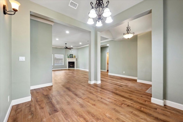 unfurnished living room featuring visible vents, baseboards, a fireplace, wood finished floors, and ceiling fan with notable chandelier