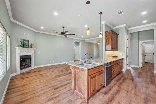 kitchen with brown cabinetry, a ceiling fan, visible vents, dishwasher, and a sink