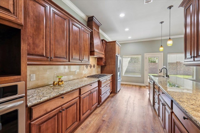 kitchen featuring tasteful backsplash, a sink, ornamental molding, stainless steel appliances, and light stone counters
