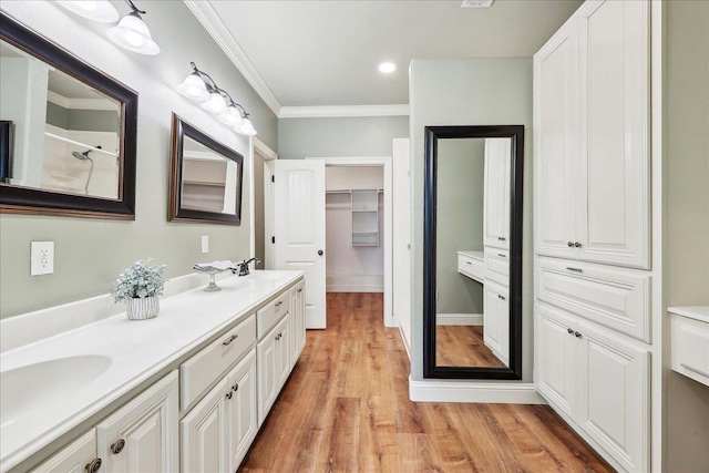 bathroom featuring crown molding, double vanity, wood finished floors, and a sink
