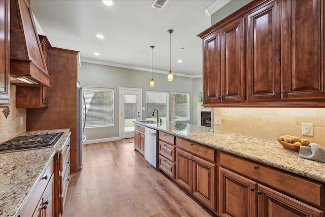 kitchen featuring appliances with stainless steel finishes, premium range hood, visible vents, decorative backsplash, and a sink
